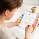 Freelancer reviewing a contract on a tablet beside a coffee cup in a bright studio